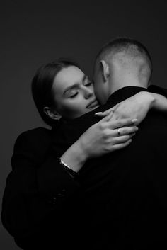 a man and woman embracing each other in black and white