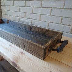 a wooden box sitting on top of a table next to a brick wall and floor