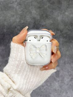 a woman holding an airpods case with a bow on the front in her hand