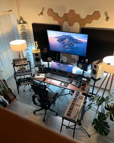 a computer desk topped with lots of electronic devices and musical equipment in front of a large screen