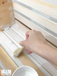 a person using a brush to paint the side of a window sill with white paint