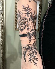 a woman's arm with flowers and leaves on it