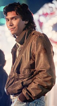 a young man wearing a leather jacket and jeans