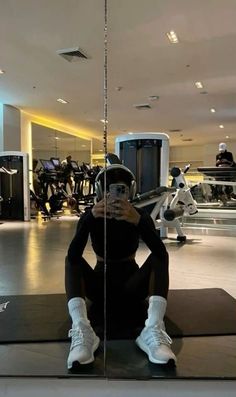 a woman taking a selfie in front of a mirror at the gym with her cell phone