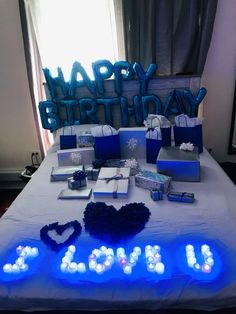 a birthday party with blue and white lights on the bed, presents are laid out in front of it