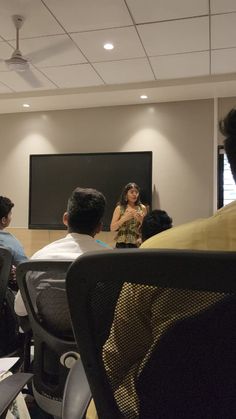 people sitting in chairs watching a presentation on a projector screen