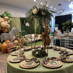 a table set up for a party with plates and place settings on it, along with balloons in the background