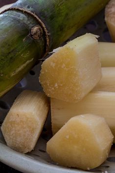 peeled bananas on a white plate with a green banana in the background and a wooden stick sticking out of it