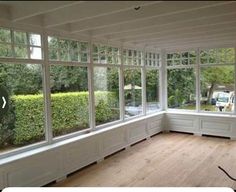 an empty room with large windows and wooden floors in front of the window are cars parked on the street