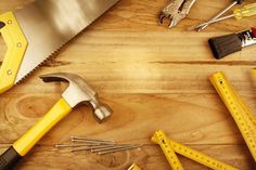 tools are laid out on a wooden surface with measuring tape, wrench and hammer