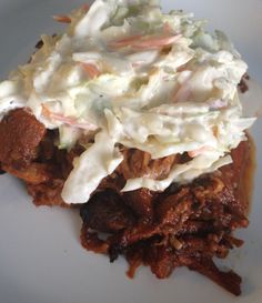 a white plate topped with meat and coleslaw covered in cream cheese on top of it