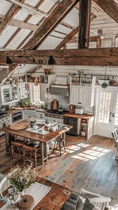 an open kitchen and dining area in a rustic style home with wood floors, white walls, exposed beams and wooden ceiling