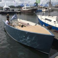 a man is sitting in a small boat on the water with other boats behind him