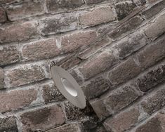 a brick wall with a round light on it's side and a hole in the middle