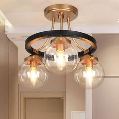 three clear globes are hanging from the ceiling in this bathroom light fixture, which is gold and black