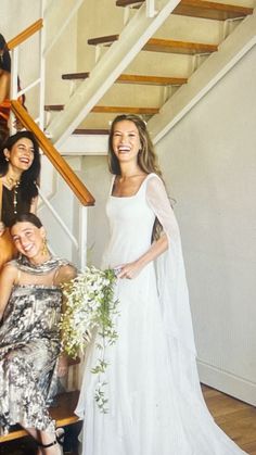 a group of women standing next to each other in front of a stair case holding flowers