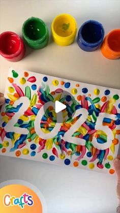 someone is holding up a paper cutout with the number 50 on it and colorful paint