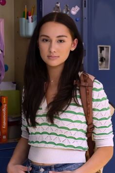 a young woman standing in front of a locker with her hands on her hips and looking at the camera