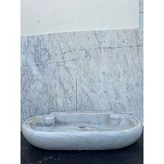 a white marble sink sitting on top of a black counter next to a large wall