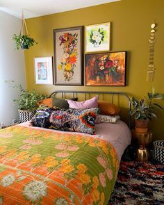 a bed sitting in a bedroom next to two pictures on the wall and plants hanging above it