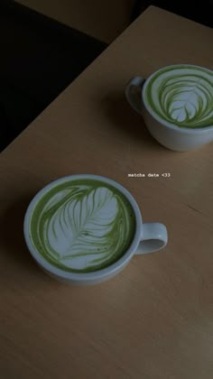 two cups with green liquid in them sitting on a table