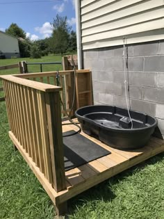 an outdoor hot tub sitting on top of a wooden deck next to a brick wall