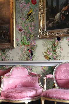 two pink chairs sitting next to each other in front of a painting