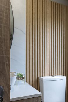 a white toilet sitting in a bathroom next to a wooden wall with vertical slats on it