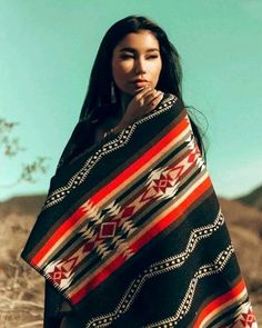 a woman is standing in the desert wearing a blanket