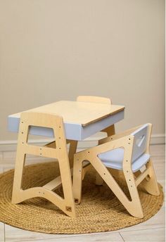 a wooden table and two chairs sitting on top of a rug in front of a wall