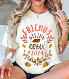 a woman sitting on top of a bed wearing a t - shirt that says friends giving crew