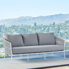 a couch sitting on top of a wooden floor next to a mountain range in the background