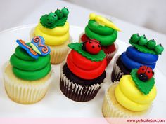 cupcakes decorated with colorful frosting and decorations on a white plate in the shape of caterpillars