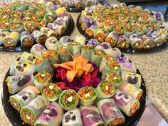 there are many different types of sushi rolls on the counter top, and one is decorated with an orange flower