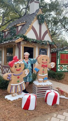 a woman standing in front of two large gingerbreads