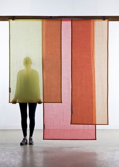 a woman is standing in front of two different colored pieces of fabric that are hanging on the wall