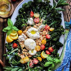 a white plate topped with broccoli, beans and tomatoes on top of a wooden table