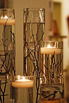 candles and flowers are arranged in glass vases