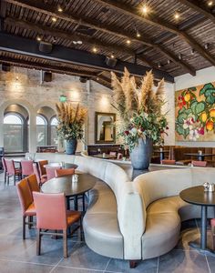 a restaurant with tables, chairs and vases on the wall above the seating area