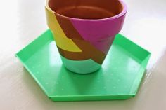 a paper cup sitting on top of a green tray next to a pink and yellow cup