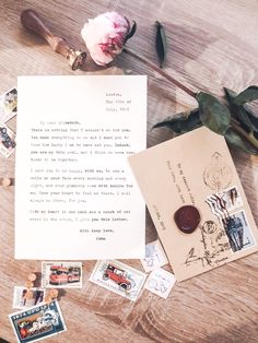 an old letter, stamp and rose on a wooden table with postcard stamps next to it