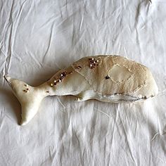 a stuffed fish is laying on a white cloth covered tablecloth with beads and sequins