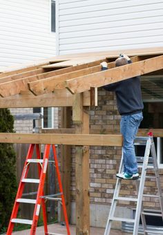 a man standing on top of a wooden platform next to a ladder and building materials