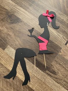 a paper cut out of a woman holding a wine glass on top of a wooden table