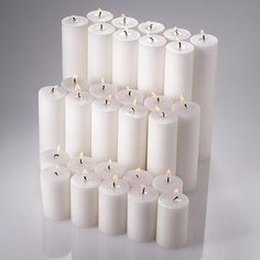 several rows of white candles with one lit in the middle and six on each side