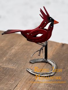 a red bird sitting on top of a metal stand