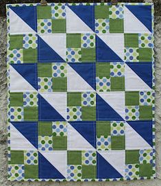 a blue and green patchwork quilt hanging on a wall