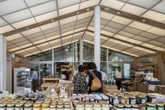 people are shopping at an outdoor market with lots of jars on the table and in front of them