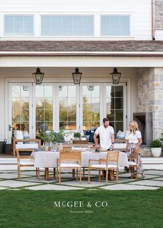 a couple sitting at a table in front of a house with the words magen & co on it