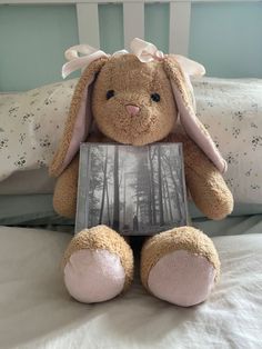 a stuffed animal sitting on top of a bed next to a box with a book in it